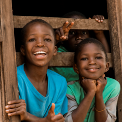 Two African boys standing in a doorway smiling