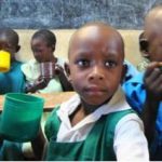 A young girl from Kenya in a classroom having a snack and drinking water