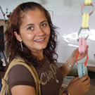 A young, smiling woman leading a workshop for teachers in a classroom